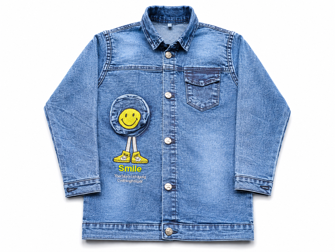 A light blue denim jacket for kids, featuring a yellow smiley face patch applique on the front pocket with the word 'Smile' written below it, shown against a plain white background.