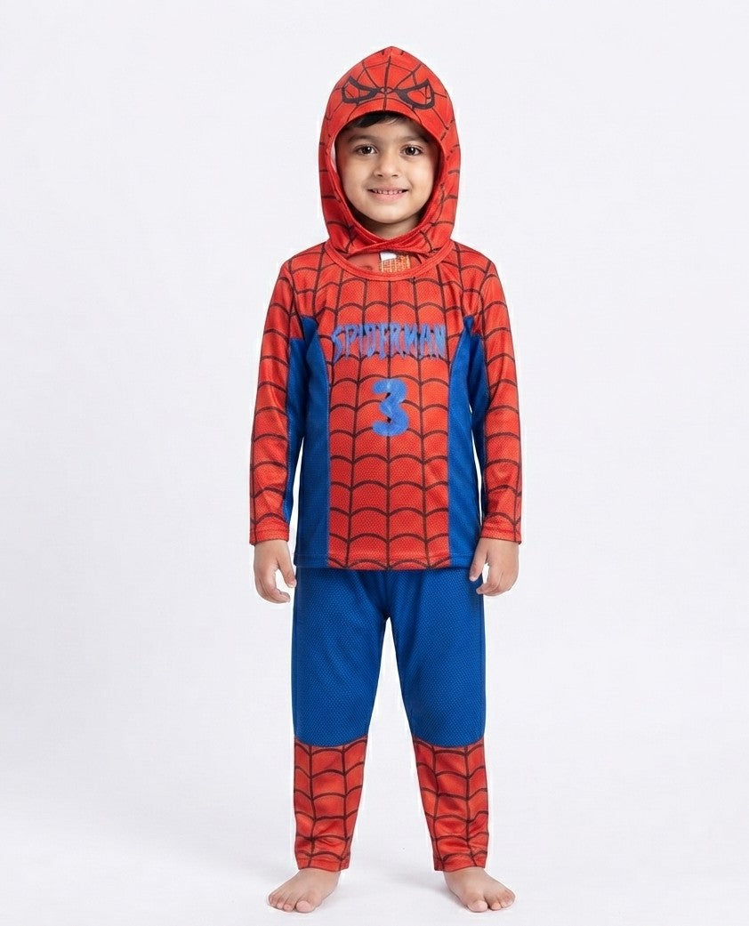 A young child wearing a Spider-Man themed hooded pajama set with a red and blue web-patterned top and matching pants, standing against a plain light gray studio background.