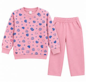 A two-piece children's pajama set featuring a long-sleeve sweatshirt and matching pants. The sweatshirt is light pink with a pattern of blue hearts, stars, and small cloud motifs.
