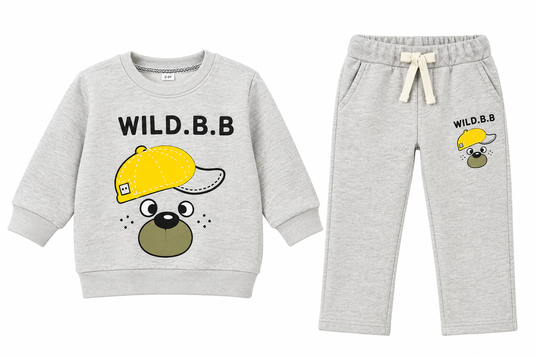 A two-piece baby clothing set featuring a light heather gray sweatshirt and matching sweatpants. The sweatshirt has a cartoon dog face wearing a yellow cap with the text 'WILD.